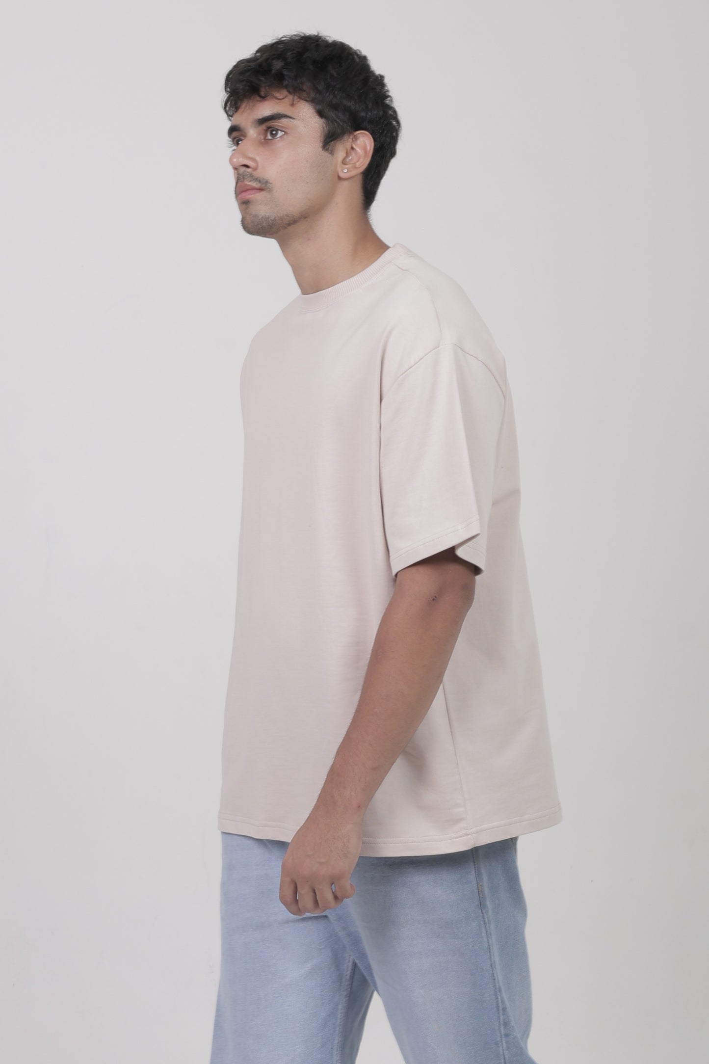 Side view of YuloLife solid beige oversized cotton terry 240 GSM tee highlighting heavyweight structure and loose fit.