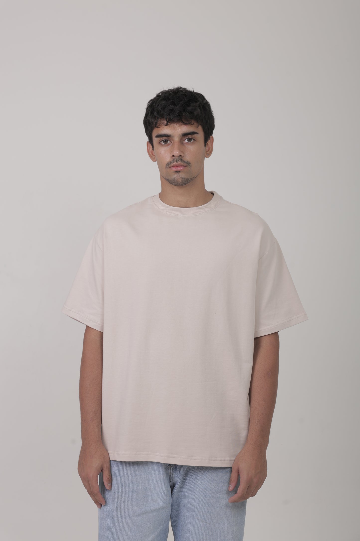 Male model wearing YuloLife solid beige oversized 240 GSM cotton terry tee, front view showing structured streetwear fit